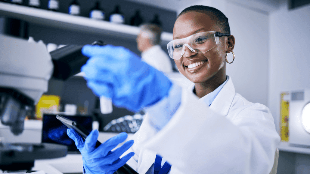 Young scientist, wearing lab coat, smiling while working.