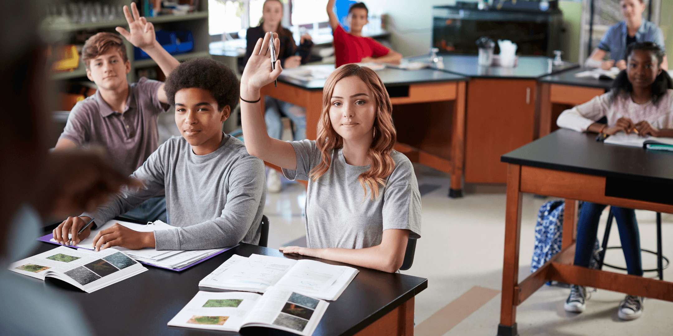 Female student in biology class raising hand to answer question.