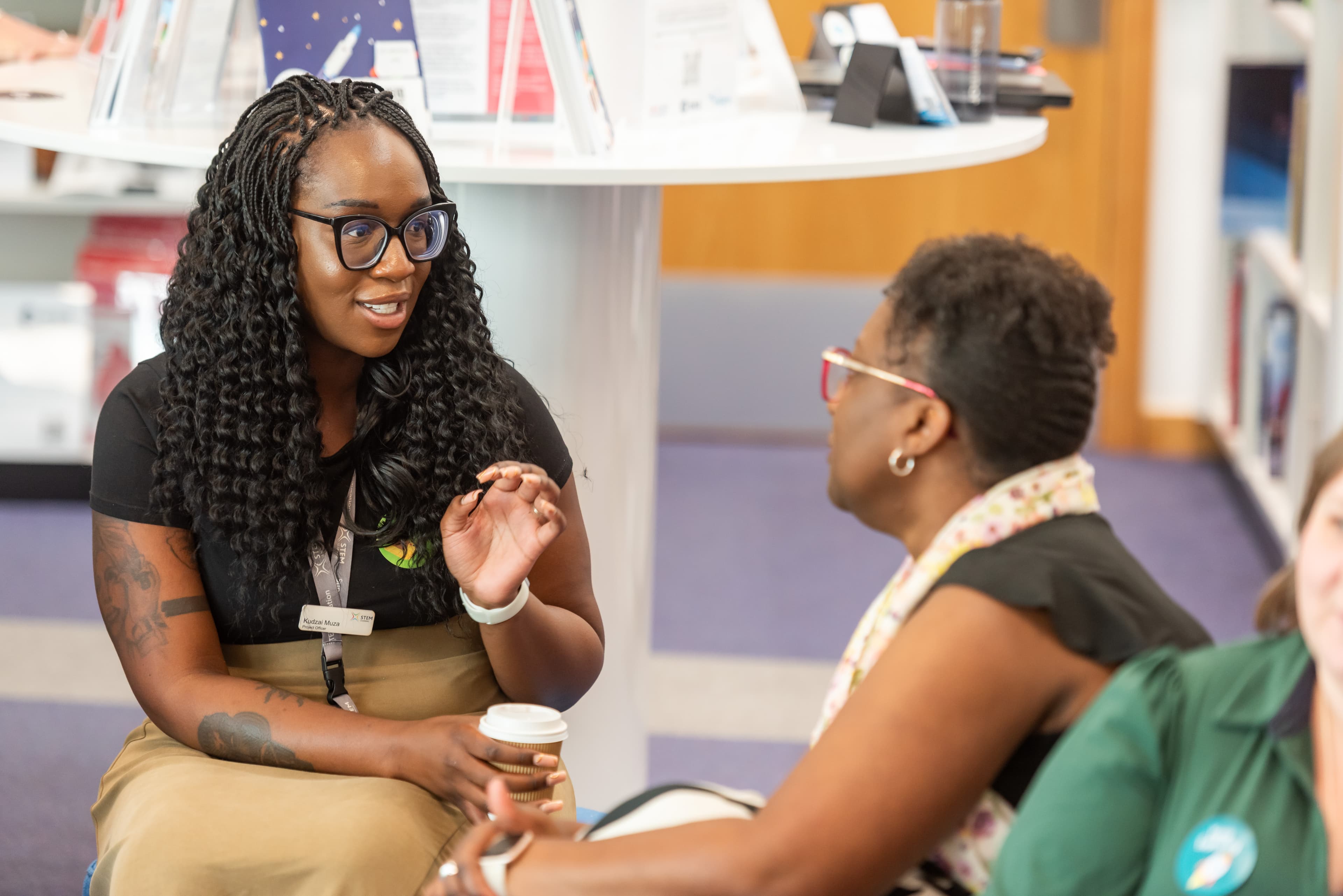 Two young women sat in a library chatting